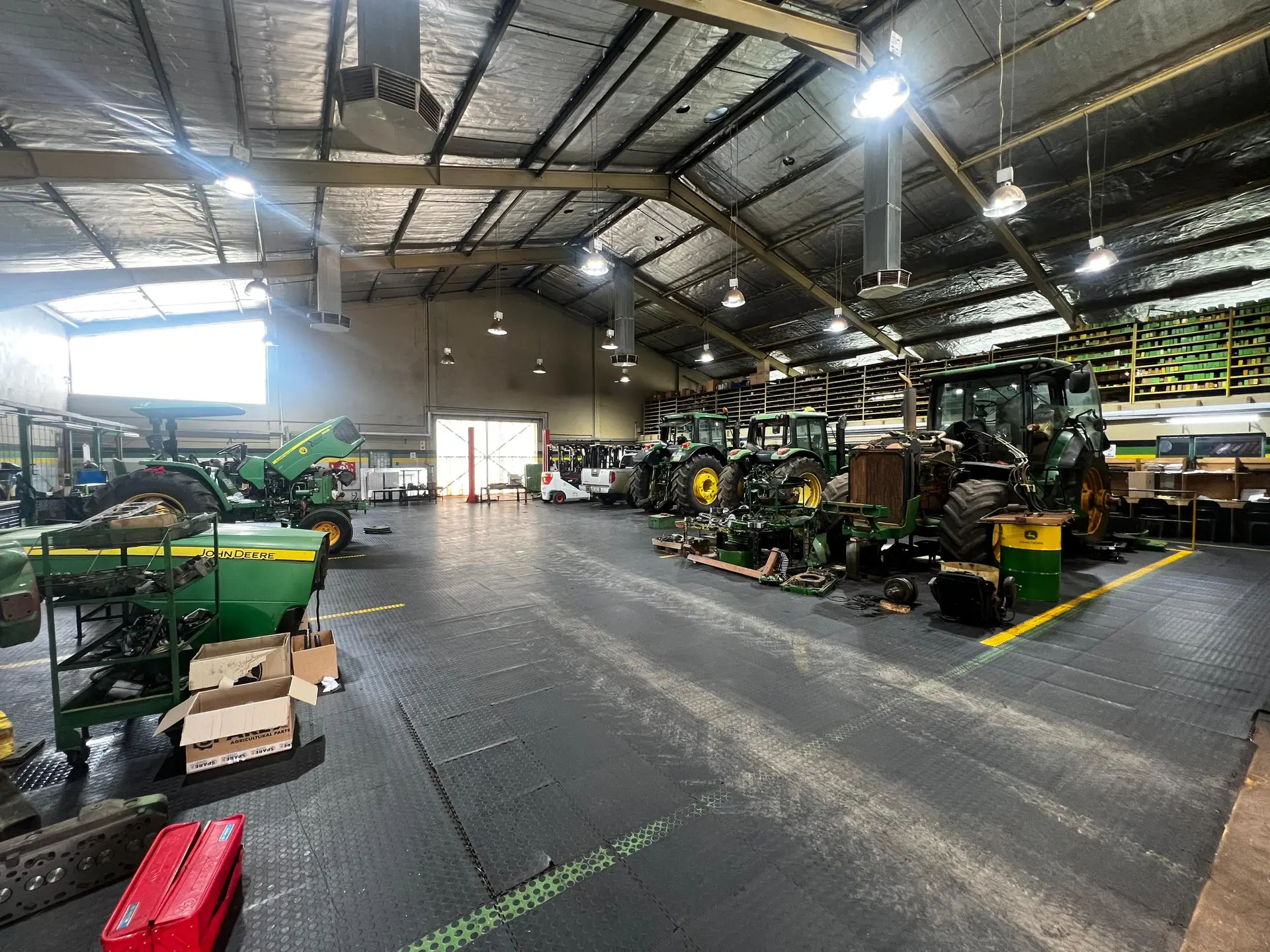 John Deere tractors with open bonnets and repair components inside SwaziTrac's Matsapha workshop